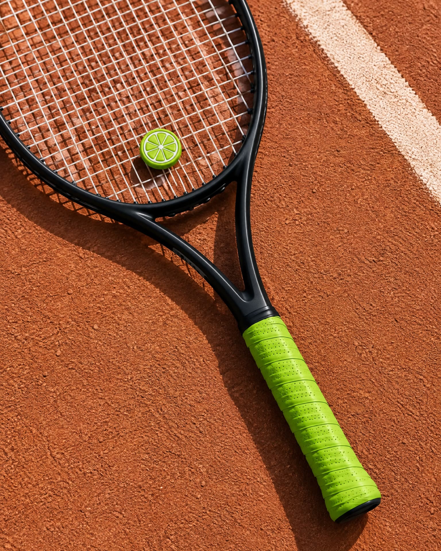 Lime Slice demper met limekleurige overgrip op een tennisracket