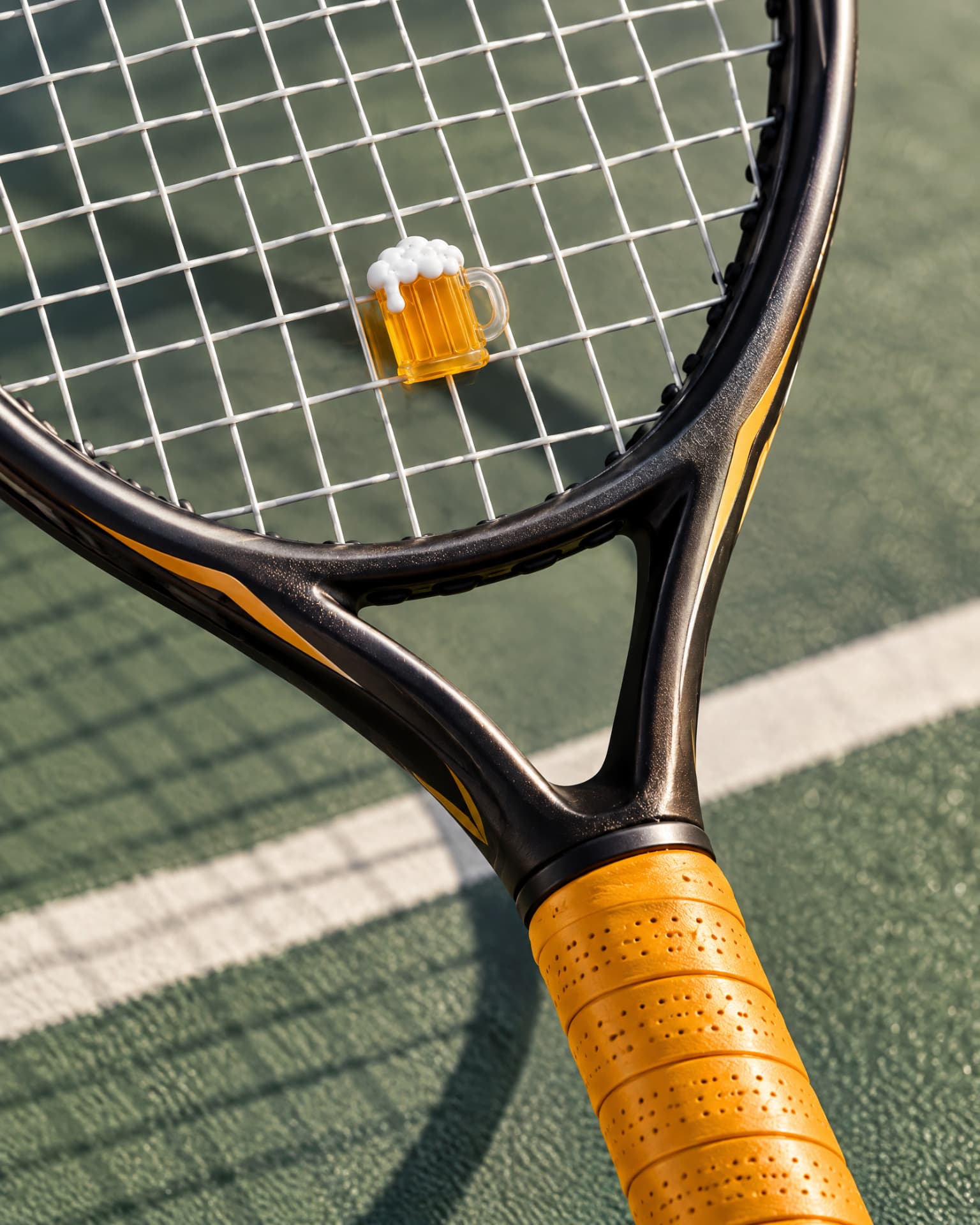 Beer Mug demper met amberkleurige overgrip op een tennisracket